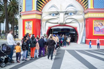 People queue at the entrance to Luna Park, Melbourne, symbolising widening access