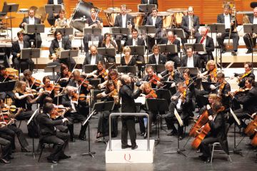 Male conductor conducting orchestral concert Male conductor conducting orchestral concert