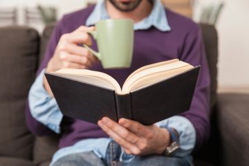 Man drinking coffee and reading book