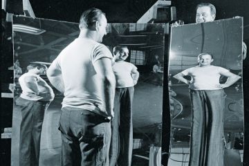 Man looking in funhouse mirror Man looking in funhouse mirror
