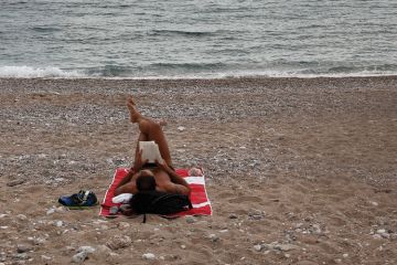 Man lying on beach, Glyfada, Greece