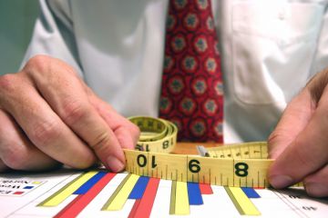 Man measuring bar graphs with tape measure