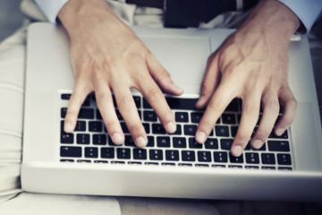 Man typing on Apple MacBook laptop keyboard