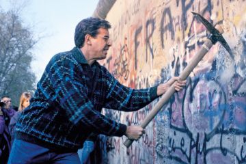 Man using pickaxe to break down Berlin Wall, 1989