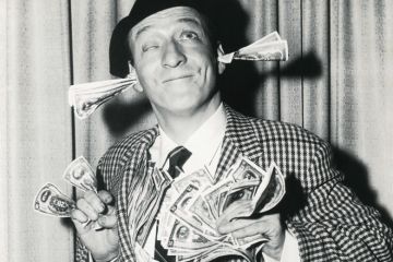 Smiling man with banknotes stuffed in ears and hands Smiling man with banknotes stuffed in ears and hands