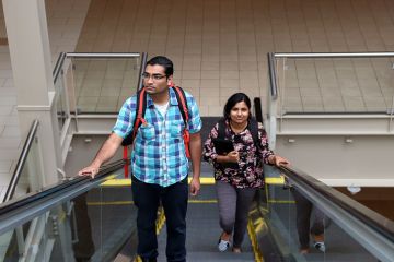 Man and woman going up escalator