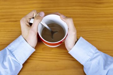 Man clutching coffee cup