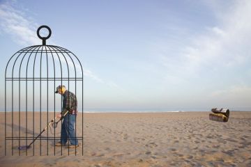 Man with a metal detector in a cage Man with a metal detector in a cage