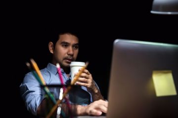 Man working at computer in evening Man working at computer in evening
