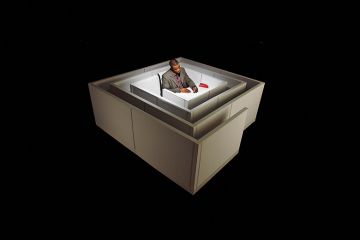 Floating in space, a black man sits at a desk in the middle of a maze Floating in space, a black man sits at a desk in the middle of a maze