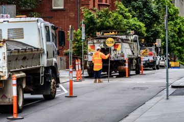 Melbourne, Victoria, Australia, October 23rd, 2021 A traffic control worker is holding a SLOW sign to slow the traffic at an inner-city construction site