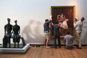 Men hanging painting on gallery wall Men hanging painting on gallery wall