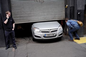Men looking at car stuck under garage door Men looking at car stuck under garage door