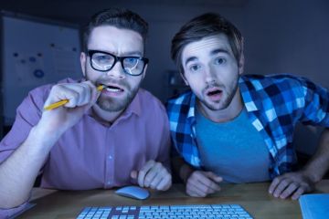 Men peering confused into computer screen Men peering confused into computer screen