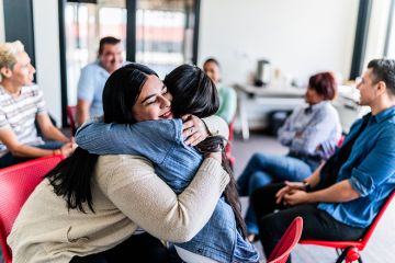 Women embracing during a group mental health session, to illustrate supporting staff mental health at universities.