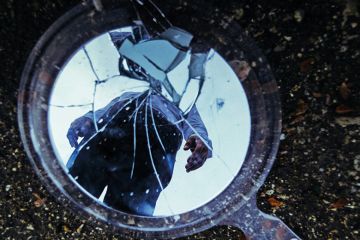 Reflection of man in cracked mirror