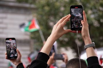 Protesters using phones to film a protest about the Israel-Gaza conflict. To illustrate students being fearful after the Trump administration’s proposal to vet all international students’ social media.