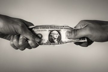 People pull on a dollar bill, illustrating competition for resources People pull on a dollar bill, illustrating competition for resources