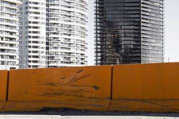 New modern inner city apartments against grungy orange road barrier.