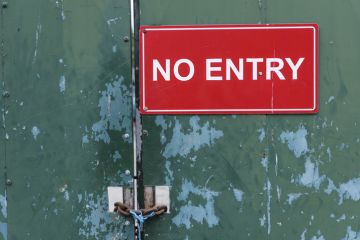 A no entry sign on a locked door illustrating visa application issues, UK Home Office, academic spouse visa
