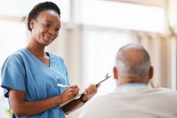 A nurse with a clipboard taking a patient’s details