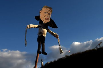 A puppet of Viktor Orban on a stick raised into the sky, symbolising his outsized influence