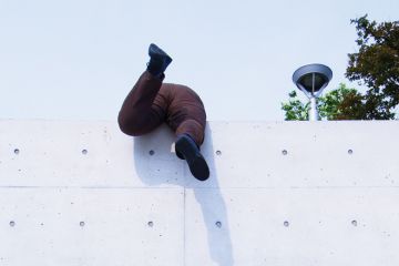 Overweight man scrambling over high wall Overweight man scrambling over high wall