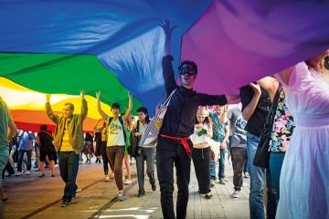 A protester in a mask holds up a Gay Pride flag during the annual Trans-sexual march on Istanbul's Istiklal Caddesi 