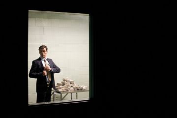 Man putting cash in his pocket behind closed door Man putting cash in his pocket behind closed door