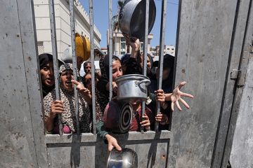 Displaced Palestinians including women and children wait to receive food distributed by aid organisations in Gaza City, Gaza on 29 May 2025. The situation highlights the growing desperation and urgent need for humanitarian assistance.