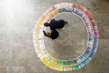 People examining circle of paint swatches, viewed from above
