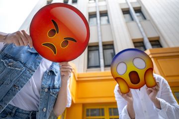 People holding the signs featuring different emoji faces. Too illustrate how neurodiverse and non-English speaking academics can be misunderstood People holding the signs featuring different emoji faces. Too illustrate how neurodiverse and non-English speaking academics can be misunderstood