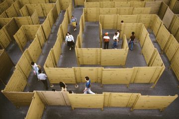 People walking through maze of wooden fences People walking through maze of wooden fences