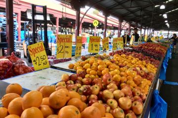 Melbourne, Australia April 12, 2018 People browse the fruit and vegetable stalls at Queen Victoria Market in Melbourne. Prices are displayed over the fruit.