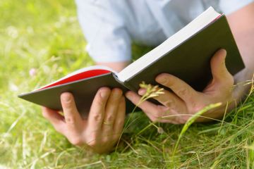 Person lying on grass reading book