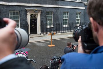 Photographers waiting for an announcement with empty lectern outside Downing Street. To illustrate that universities waiting for government intervention are likely to be disappointed.