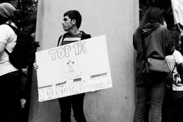 Portland, Oregon, USA - October 6, 2011 A young man holds a sign that reads Top 1٪​ Y U No Pay Taxes during an Occupy Wall Street event in downtown Portland.