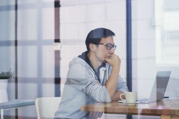Portrait of Asian businessman thinking when working on computer in office