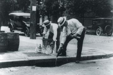Men pouring alcohol down drain during prohibition