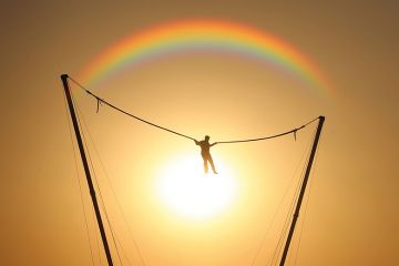 person bouncing in front of rainbow