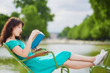 A woman reading a book in the park, symbolising neglect of teaching duties