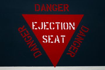 Red ejector seat warning sign on jet fighter aeroplane fuselage