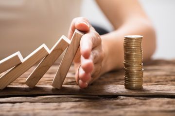 istock risk dominoes falling onto a pile of coins