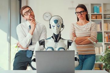 Two people scrutinise a robot