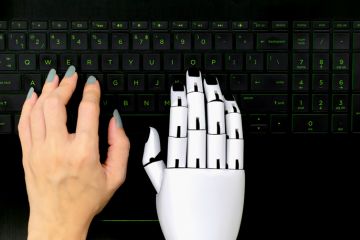 A robot and human hand on a computer keyboard, symbolising AI-assisted writing