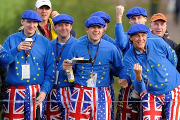 Golf fans wearing flags of the UK, EU and USA at the Ryder Cup golf competition between US and Europe. To illustrate that the UK and Europe should woo disaffected American scientists.