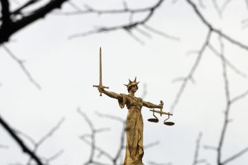 A statue of the scales of justice stands above the Old Bailey, London. To illustrate 