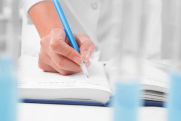 Scientist writing in notebook in laboratory Scientist writing in notebook in laboratory
