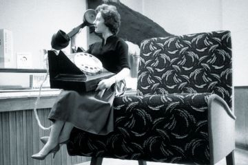 Seated woman using huge telephone Seated woman using huge telephone