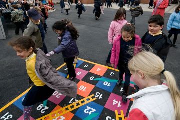 Children playing snakes and ladders in a school playground. To illustrate that the channelling of government funding into charity at the expense of universities has yet to be proven.